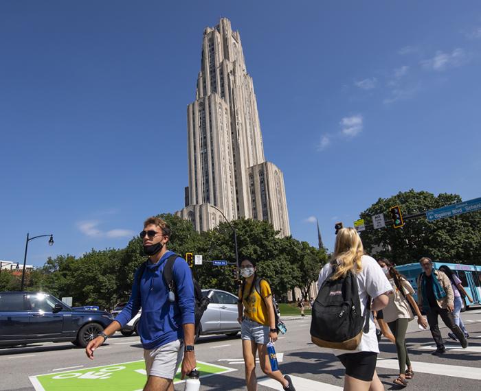 Students crossing a street in front of the Cathedral of Learning
