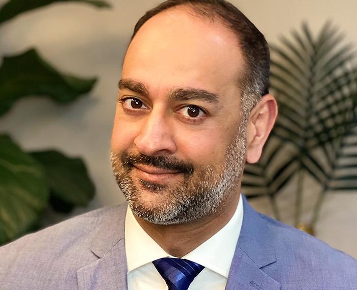 Jeffer Choudry smiling in grey suit