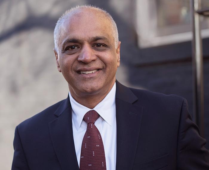 Anish Kumar wearing black suit with dark red tie