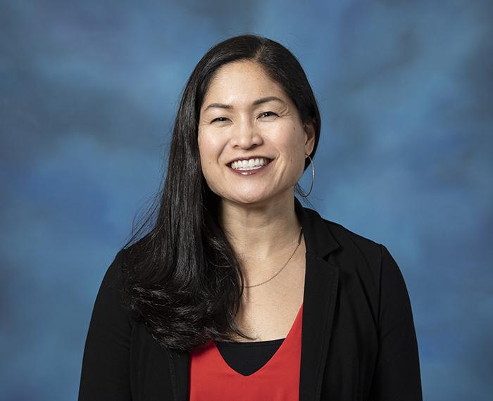 Kari Kokka smiling in front of blue background