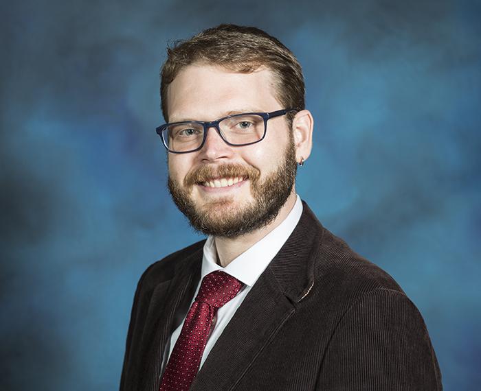 Will Evans smiling in front of blue background