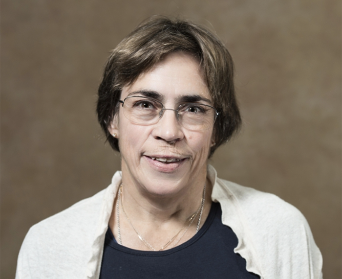 Jessie VanSwearingen smiling in front of brown background