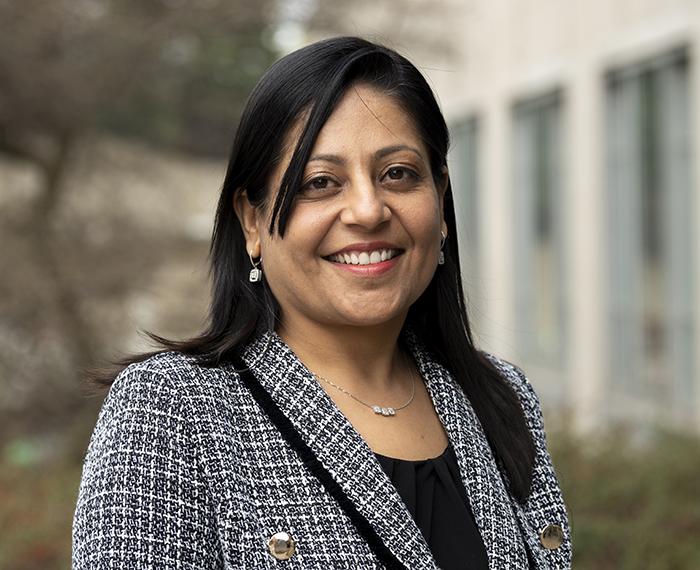 Manisha Jhamb smiling in grey suit outside