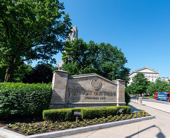a Pitt sign outside the Cathedral on a blue-sky day