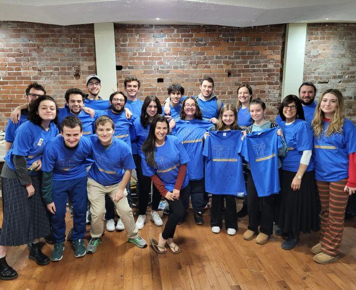 A group wearing matching blue shirts that read Twerski Fellows Program smile.