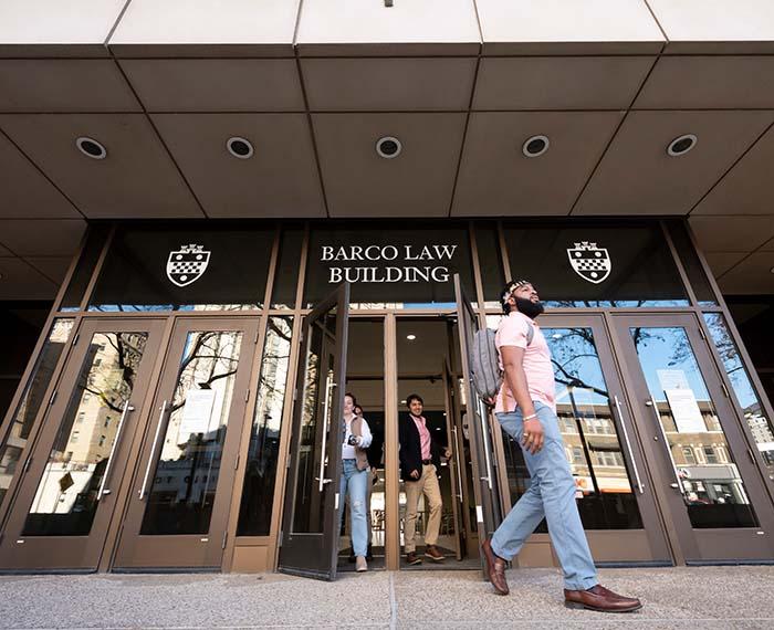 People exit through glass doors at the Barco Law Building