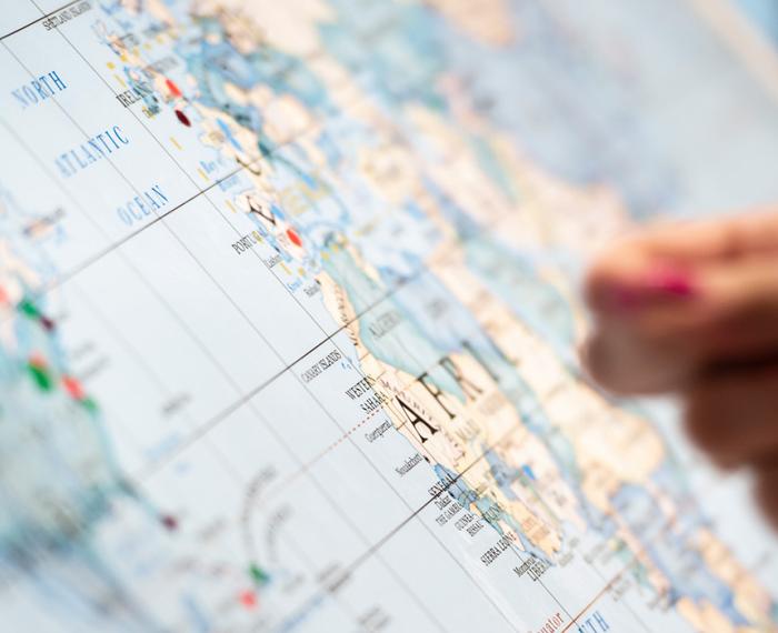 A hand reaches to put a sticker on a map