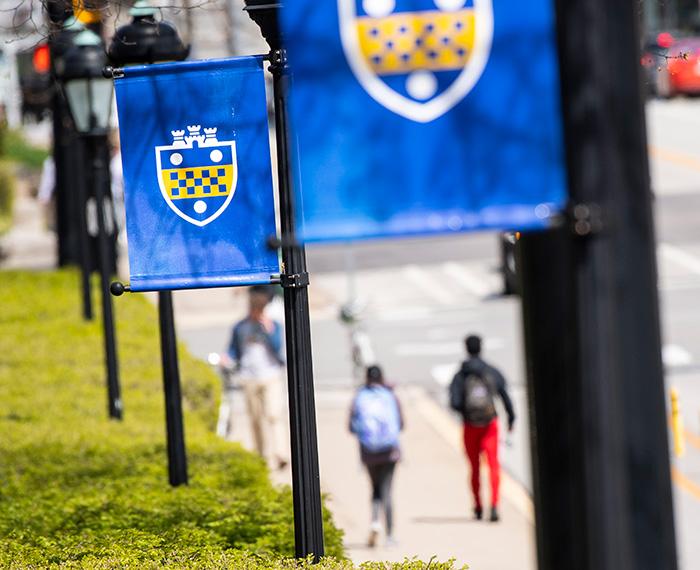 Blue Pitt flags hang on poles beside a sidewalk