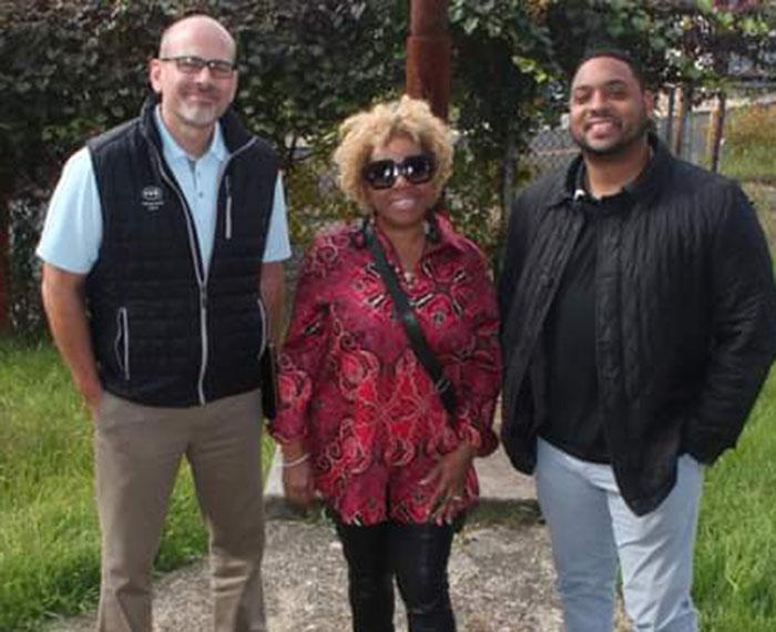 A person in a black vest, a person in sunglasses and a red shirt and a person in a black jacket