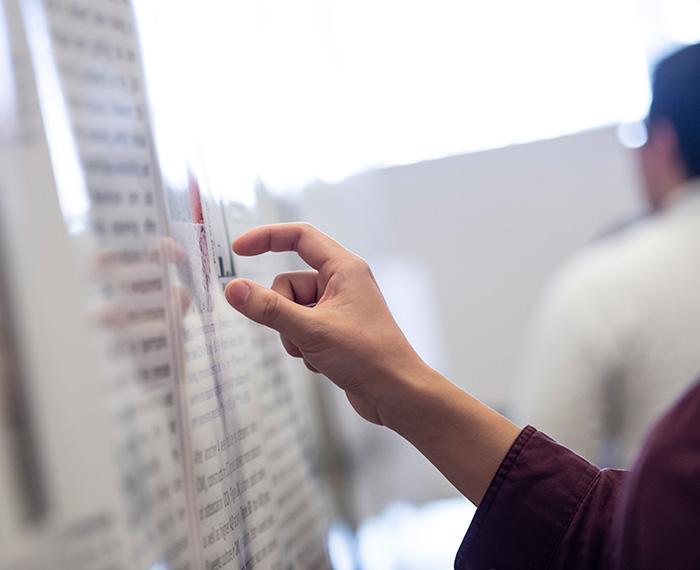 A hand points at graphs on a poster