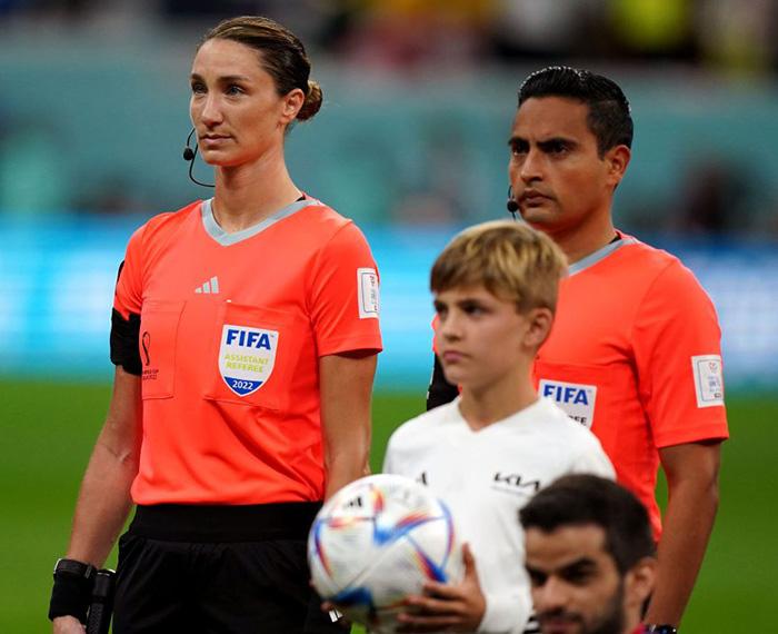 Two referees stand in orange shirts