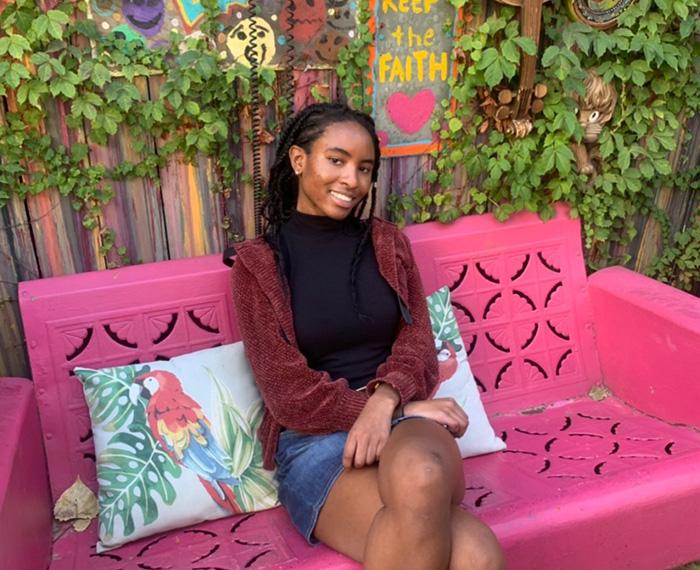 A person sits on a bright pink bench