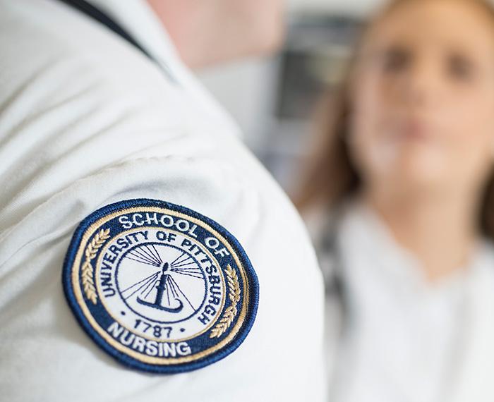 A University of Pittsburgh School of Nursing patch on a white coat