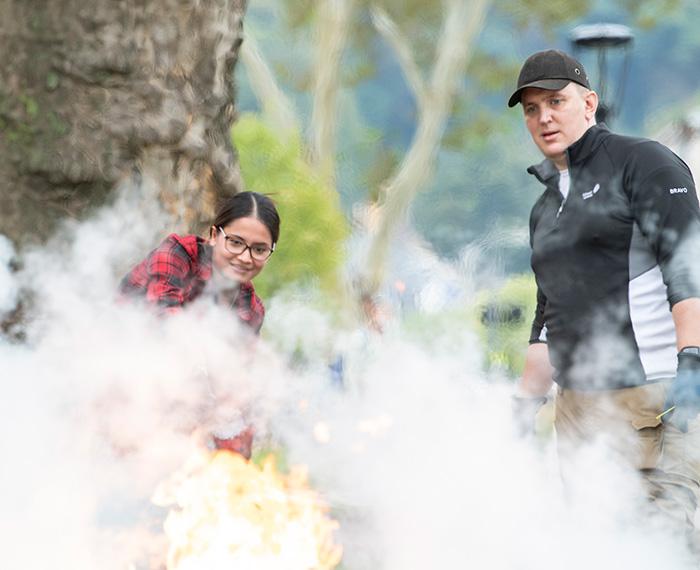 A person discharges an fire extinguisher onto a controlled flame.