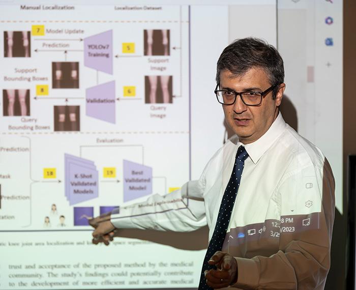 Tafti points at a projected presentation