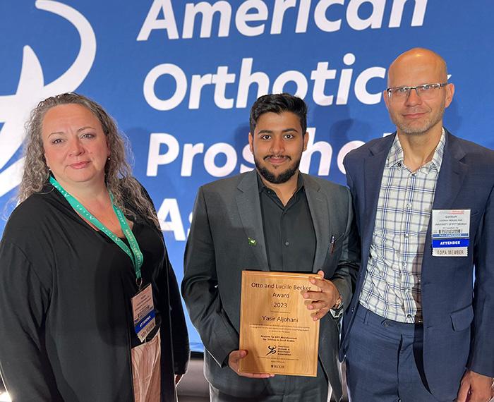 A person holds a wood plaque between two professionals