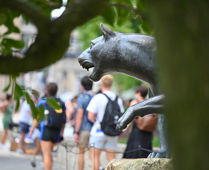 People walk past a panther statue on Pitt's campus