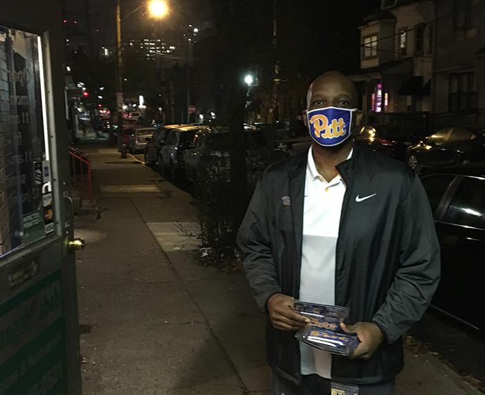Bonner stands on an Oakland sidewalk at night, wearing a Pitt script mask