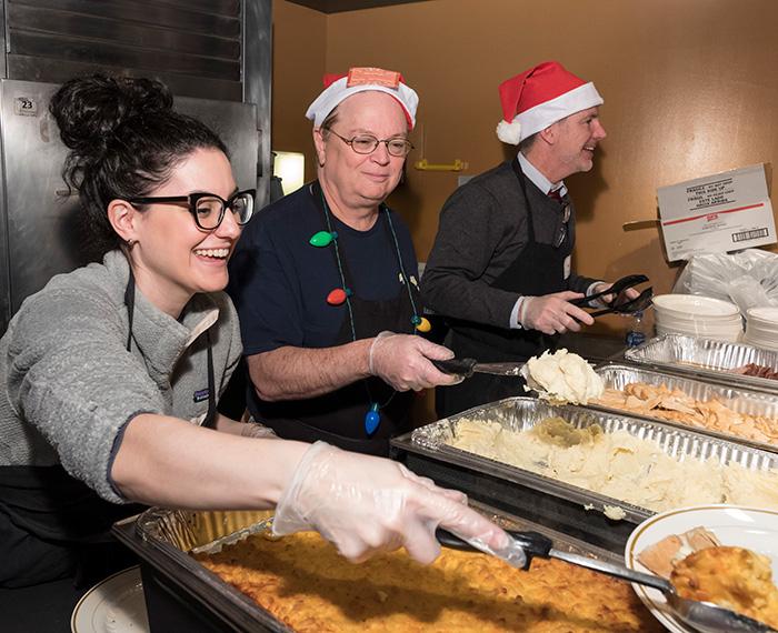 Volunteers behind a counter serve food