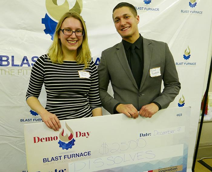 Two people hold up a giant check