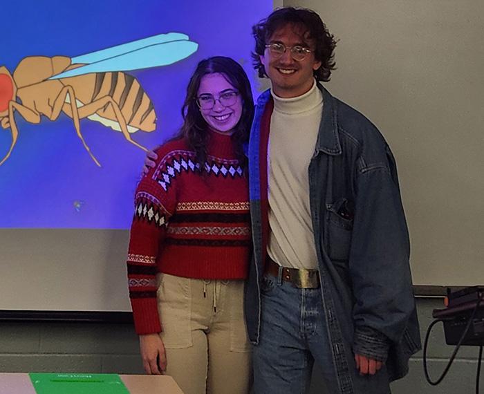 Podob and Crookston stand side-by-side in front of a projector