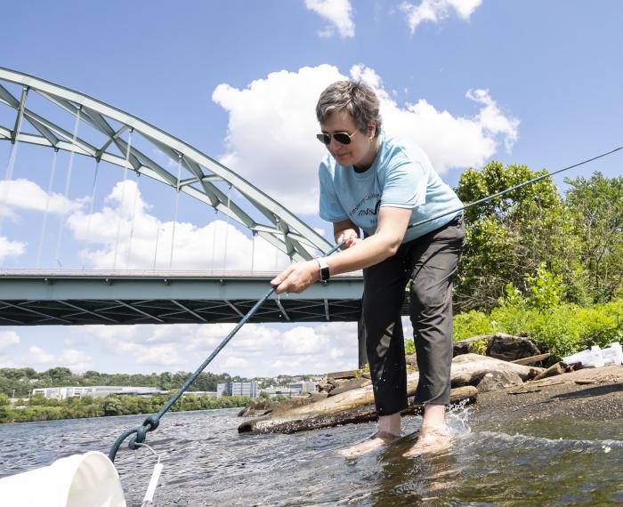Emily Elliott casts a bucket into a river