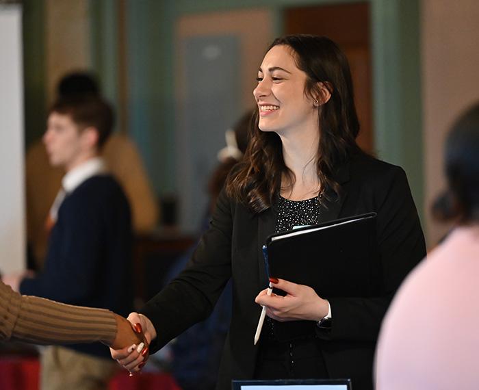 A career fair attendee shakes someone's hand