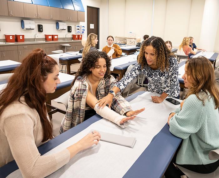 Students look at a practice splint as a professor talks