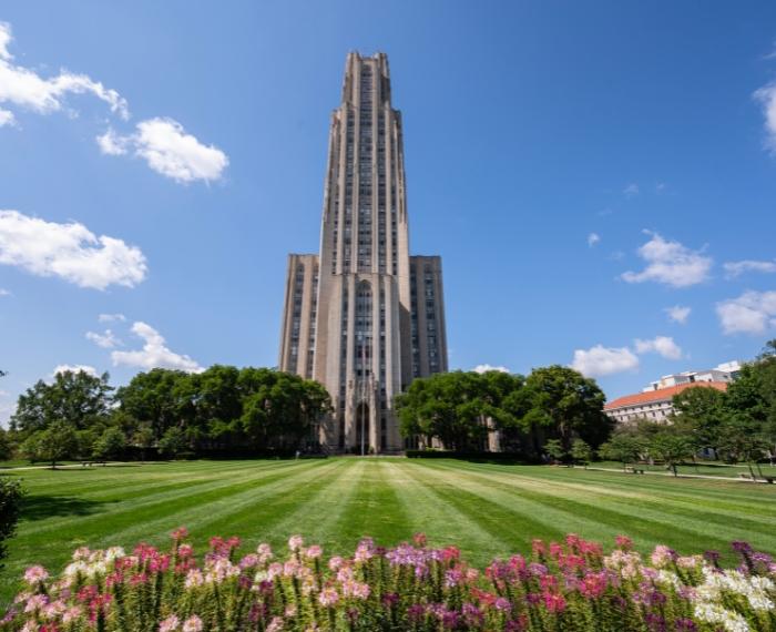 The Cathedral of Learning is shown with vibrant greenery and flowers.