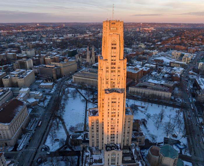 Aerial view of the Cathedral of Learning and campus at sunset during the winter.