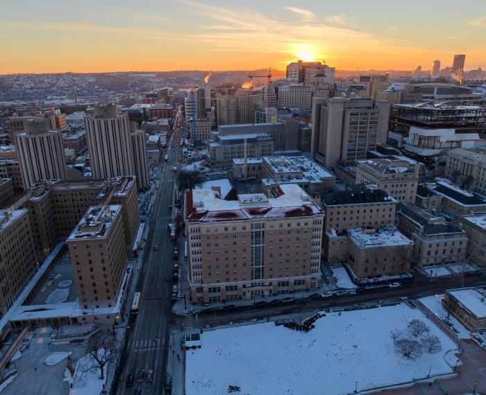 A snow-dusted campus is set against the backdrop of a sunset.
