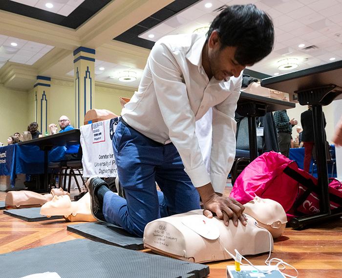 A person practices CPR on a practice dummy.