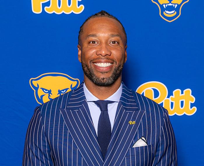 Fitzgerald stands in front of a Pitt branded background.