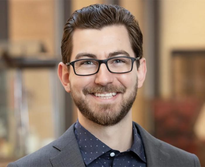Headshot of Lucas Hill in a grey suit