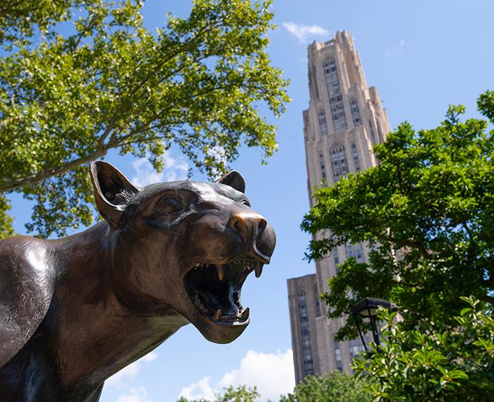 Summer image of the panther statue with the Cathedral of Learning behind it