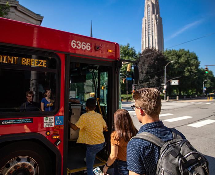 People board a red city bus in Pittsburgh's Oakland neighborhood.
