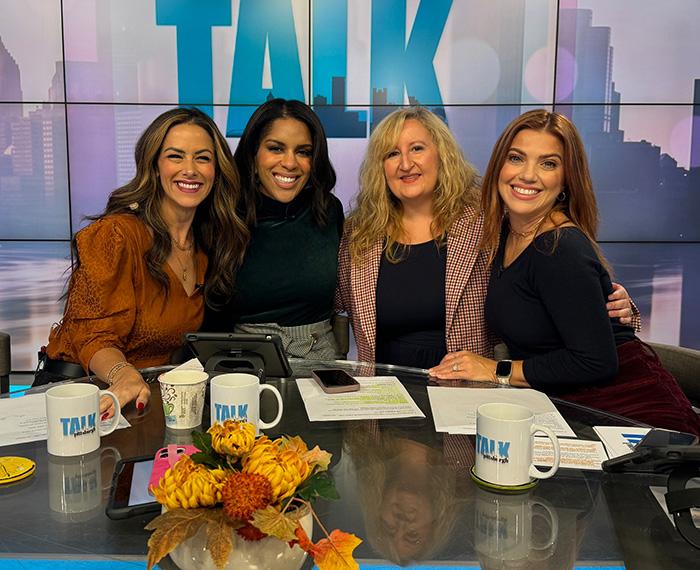 Jessica Ghilani (pictured, second from right) sits with 3 other women with a screen that reads TALK behind them