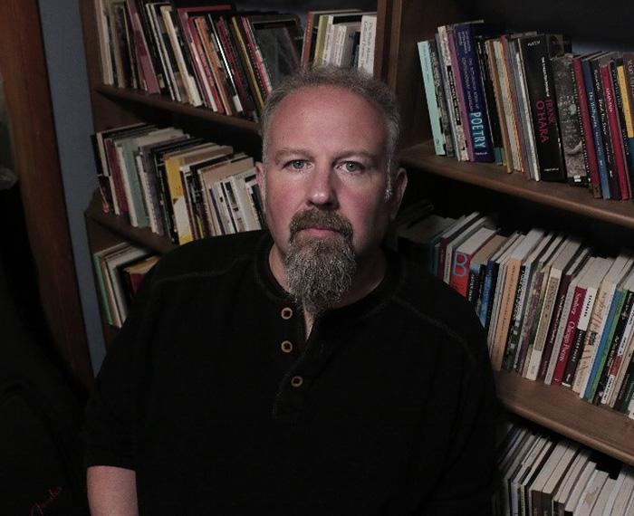 Dave Newman sits in front of a bookcase