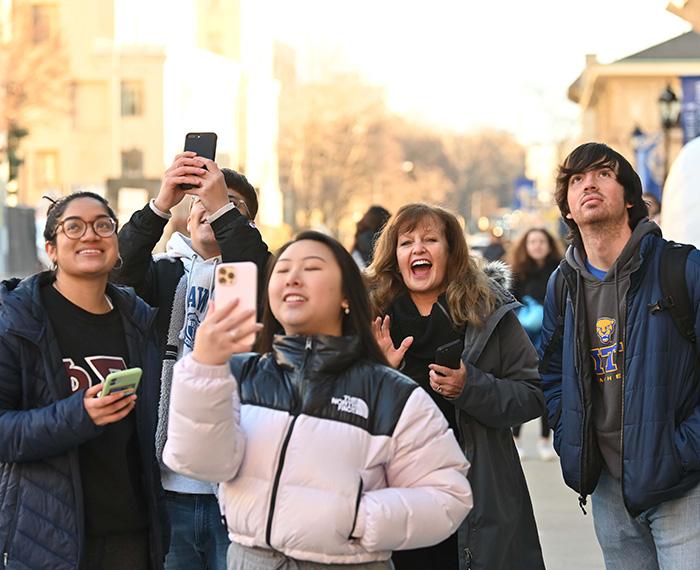 Bayles smiles as students hold up their phones to take photos.