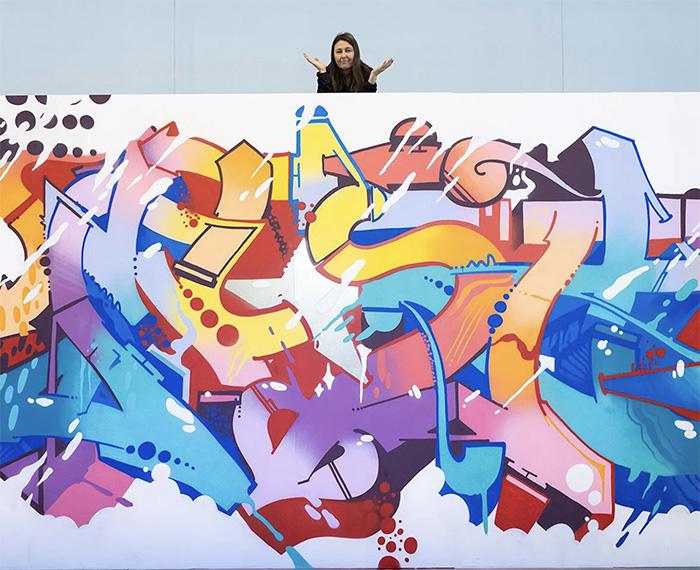 Woman stands on the top of a white wall graffiti art