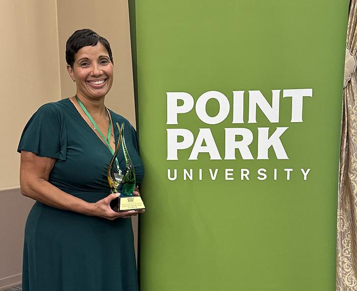 McClure stands next to a Point Park University banner.