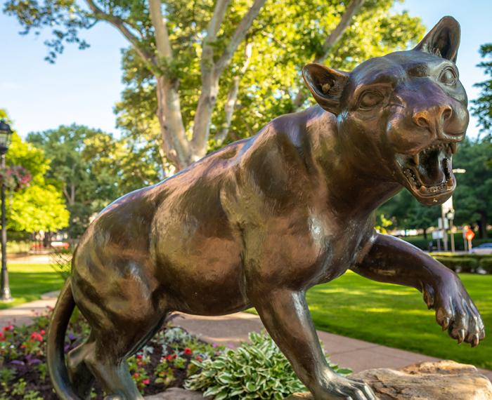 Bronze Panther statue with red flowers at its base