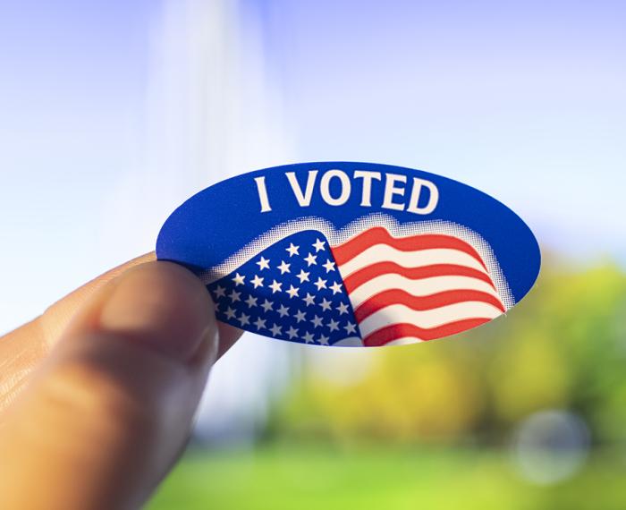 A hand holding an "I Voted" sticker