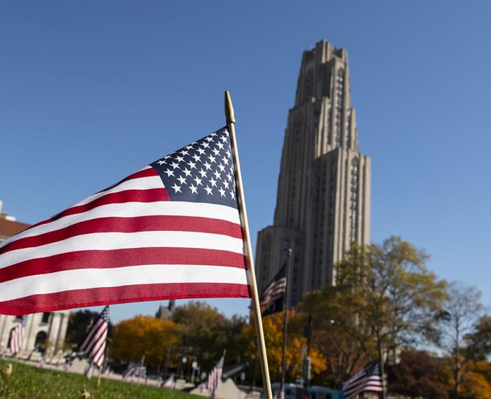 An American flag in the lawn in front of the Cathedral of Learning