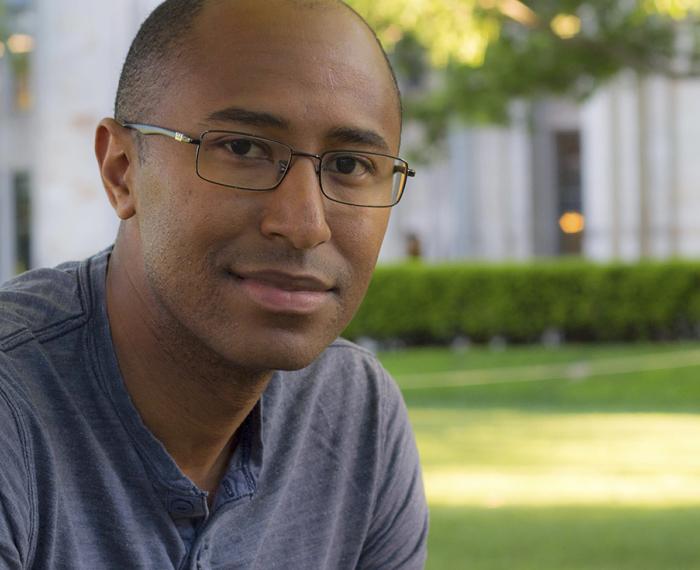 Cameron in a blue-gray shirt and thin wire glasses