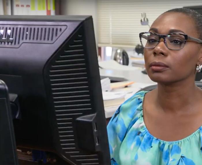 A person in a blue shirt on a computer