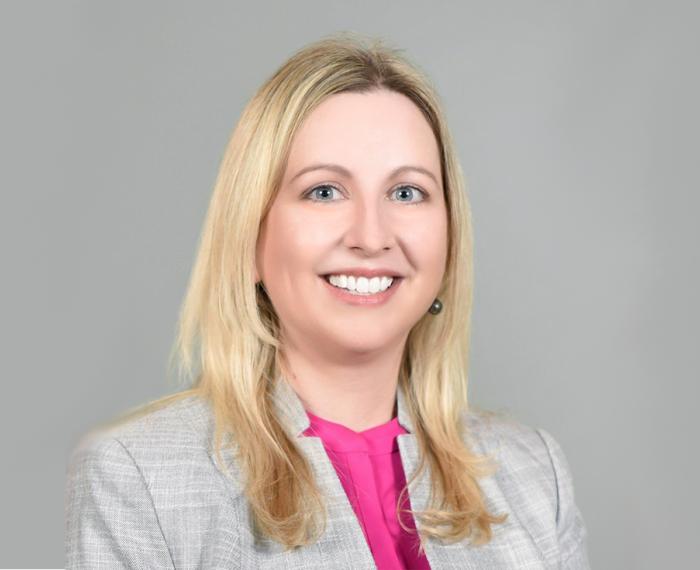 Nicola Foote in a pink shirt and gray suit jacket