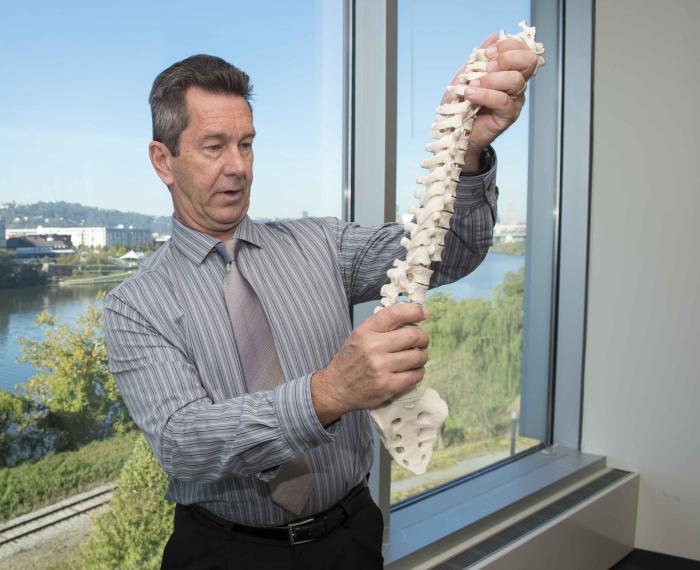 Schneider holds up a spine replica