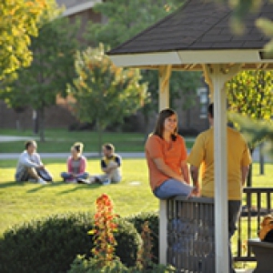 Students sitting out on a lawn and in a gazebo at Pitt Bradford campus