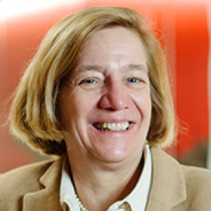 Sabine Deitrick against a red background in a beige jacket
